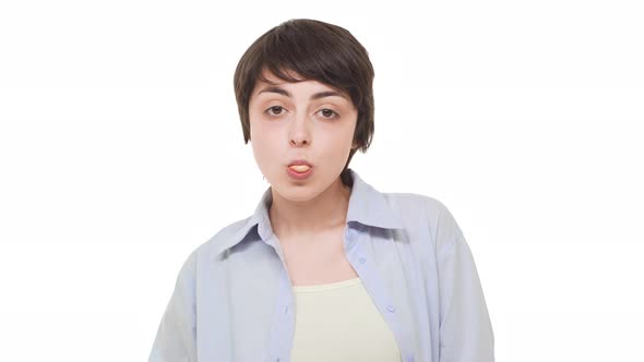 Young Caucasian Girl with Brunette Short Hair Chewing Gum and Blowing Bubble Over White Background
