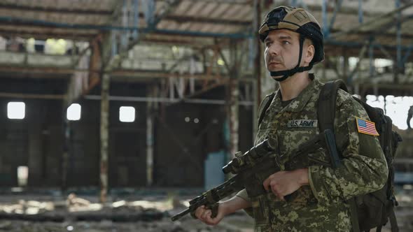 American Soldier with Gun in Hands Walking on Old Factory