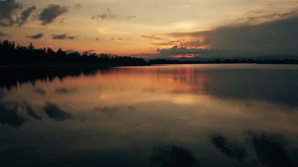 Summer red sunset over the lake and pink sky with clouds