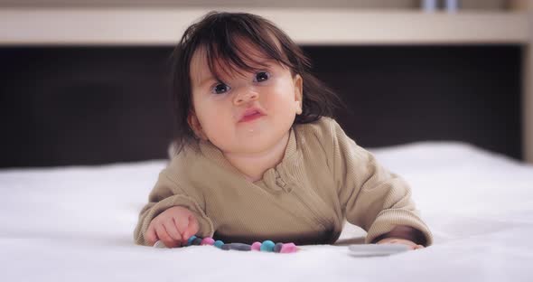 Funny Baby Girl is Lying on Her Stomach Smiling and Kicking Her Feet