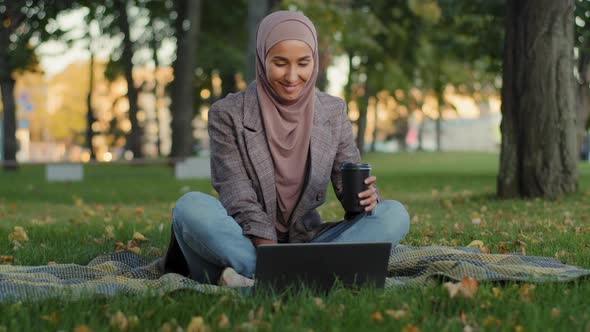 Happy Smiling Muslim Islamic Business Woman Girl Female Student Wears Hijab Sitting on Green Grass