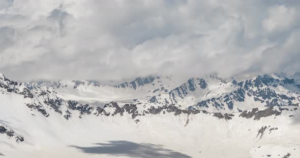 Air Flight Through Mountain Clouds Over Beautiful Snowcapped Peaks of Mountains and Glaciers