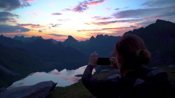 Young Woman Make Photo of Sunset Background Mountains