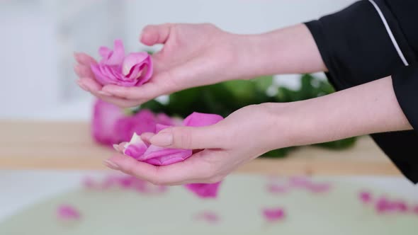 Female Hands Pour Rose Petals Into the Bath