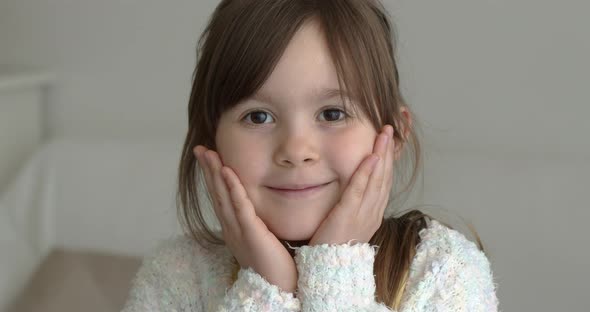 Adorable Little Girl Looking at Camera with Hans on Her Cheeks