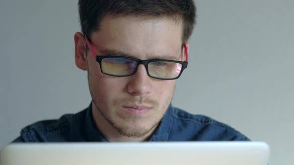 Man in Eyeglasses Working on Laptop on White Background