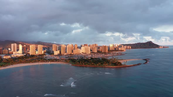 Wide descending aerial shot of Magic Beach in Honolulu, Hawaii at sunset. 4K