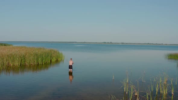 Aerial Drone View. A Man Stands in the Lake and Fishing in Summer Morning