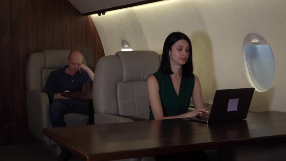 A Young Business Couple Flying In Their Private Jet Business Jet, A Girl Working At A Computer