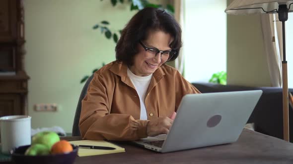 Woman Working with Laptop and Sitting at Table in Home Office During Quarantine