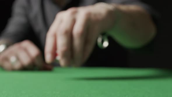 Poker Game a Man Doing a Bet Red Chips Scattering Over Green Table Towards