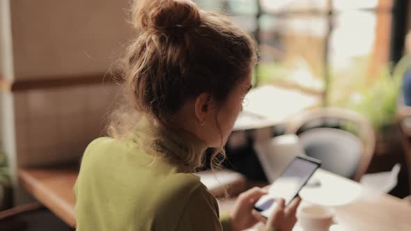 Woman Using Mobile Phone Sitting in a Cafe