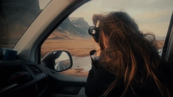 Female taking photos by camera from car