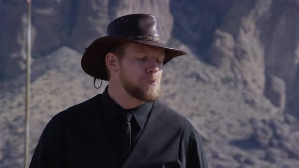 Cowboy spitting in front of mountain background