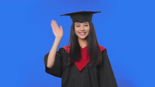 Portrait of Female Student in Cap and Gown Graduation Costume Waving Hand and Showing Gesture Come