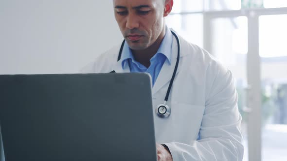 Male doctor using laptop in office 4k