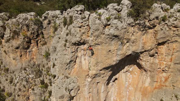 Aerial View From Drone of Strong Athletic Man Rock Climber Descends From High Vertical Cliff on Top