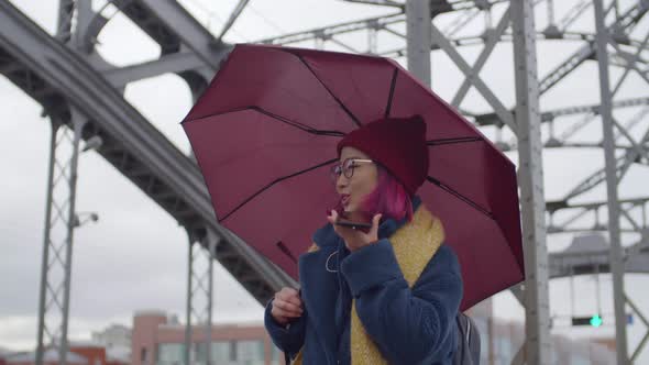 Asian Woman Walking with Umbrella and Chatting via Speaker Phone