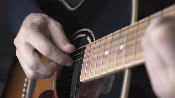 Person in Pullover Plays Old Black and Brown Guitar Closeup