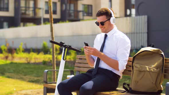 Businessman with Cellphone, Headphones and Coffee