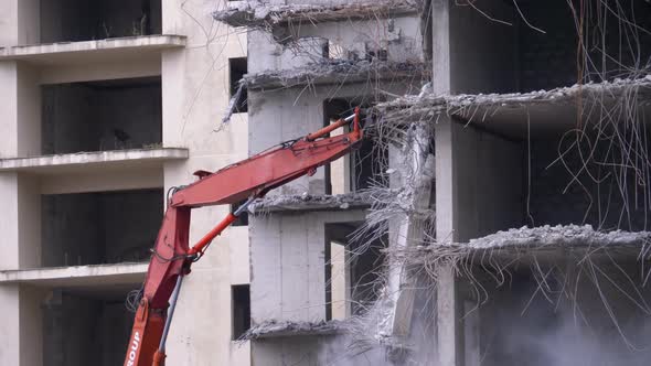 Destroying Old Concrete House Using Mechanical Arm of Bulldozer on Construction Site alt