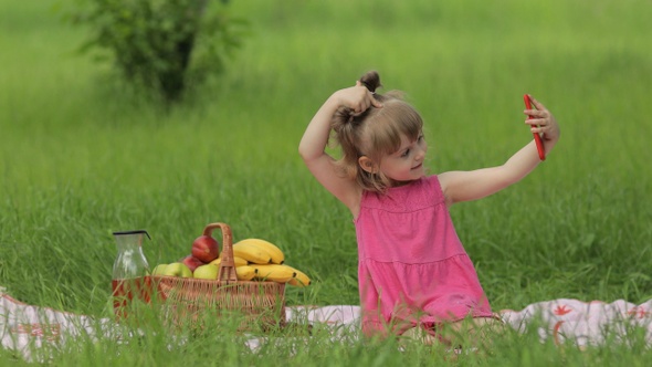 Weekend at Picnic. Girl on Grass Meadow Makes Selfie on Mobile Phone. Video Call, Blog, Play Games