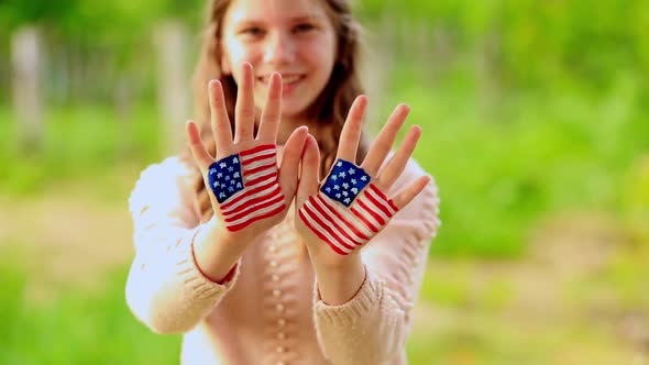 Cute Teenager Girl Waving Greeting with Painted Hands in American Flag Color