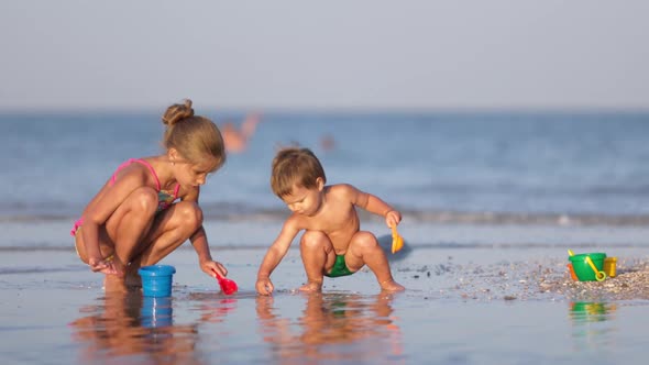 Older Sister Playing with Younger Brother Aground Near the Shore on Summer Vacation