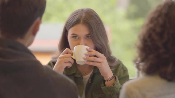 Portrait of a Cute Girl Sitting in a Restaurant in the Company of Friends