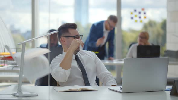 Young Happy Businessman Working on Computer and Throws Up Papers in Office