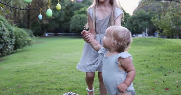 Two Children Wearing Bunny Ears When Pick Up Painted Easter Egg Hunt In Garden or Park