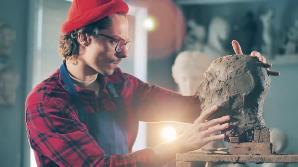 A Man is Observing a Clay Sculpture Kneaded By Him