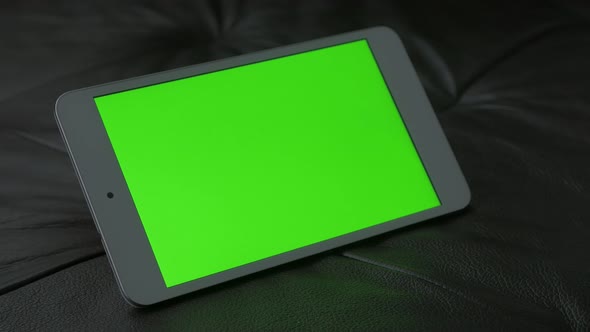 Exposed tablet with green screen display on couch 4K 2160p 30fps UltraHD footage - Chroma key green 