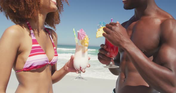 African american couple drinking cocktail seaside