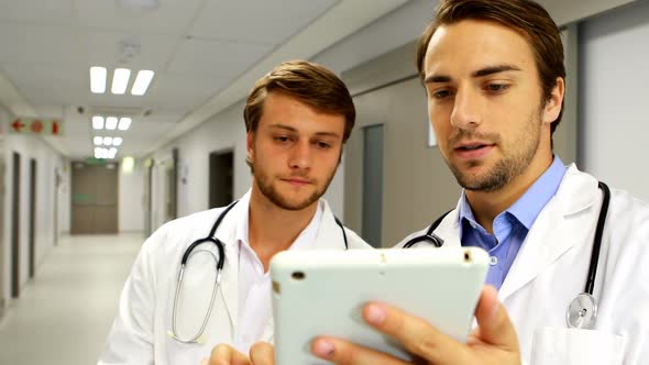 Doctors discussing over digital tablet in corridor