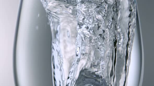 Extreme slo-motion close-up ice dropped into water glass, Slow Motion