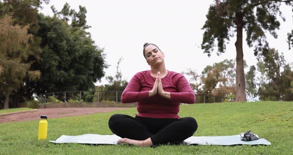 Curvy young woman doing yoga exercise at park