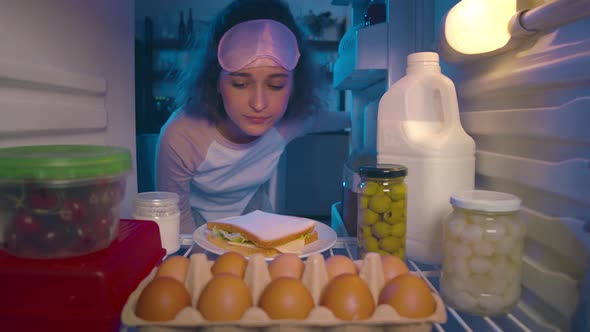 Young Woman Taking Food From Fridge Late at Night