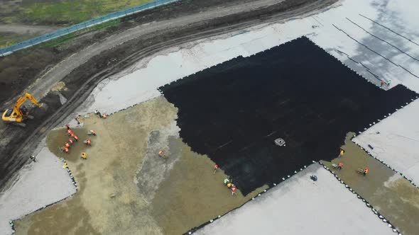 Builders Put Sand Onto Black Grid at Construction Site