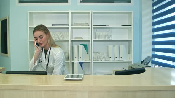 Female Nurse at Hospital Reception Answering Phone Calls and Scheduling Patient Appointments