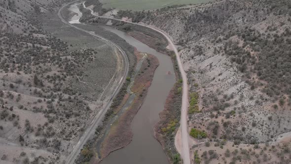 Sedan driving along the Colorado River on a remote road.