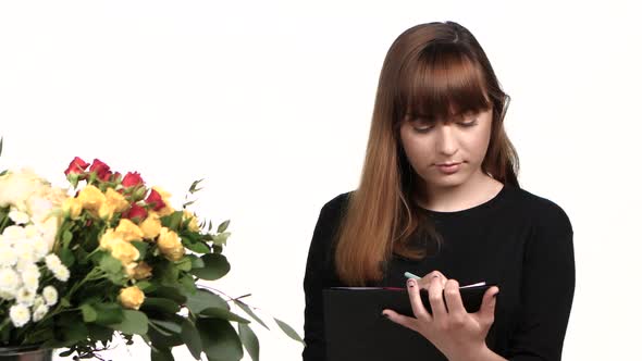 Florist Is Writing Into Her Workbook. White. Close Up