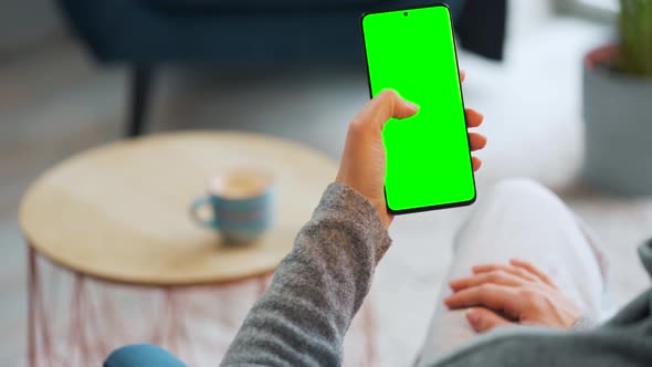 Woman at Home Using Smartphone with Green Mockup Screen in Vertical Mode