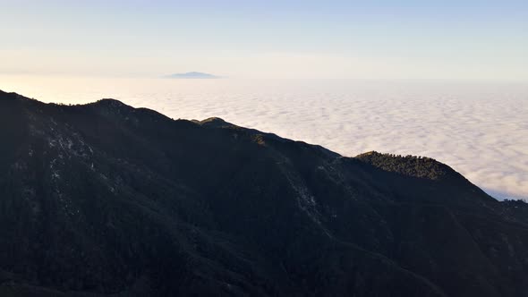 Aerial of mountains above low clouds at dawn