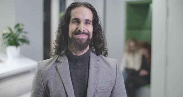 Portrait of Happy Middle Eastern Man with Long Curly Hair in Formal Business Suit Looking at Camera