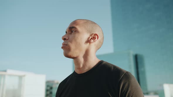Strong bald sportsman wearing black t-shirt looking around outdoors