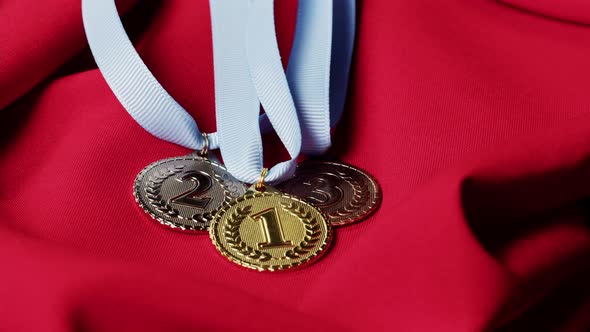 Gold Silver and Bronze Medals with Ribbons on Red Background Closeup