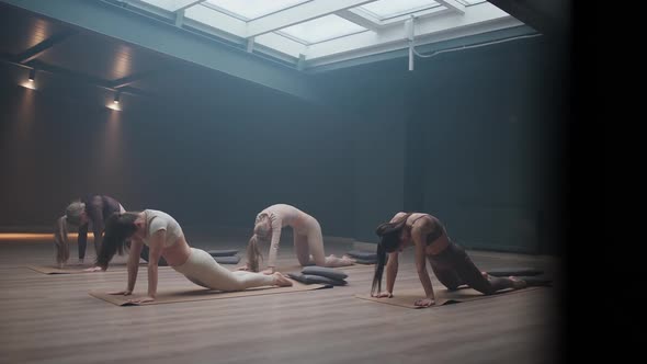 Cinematic Group of Girls Doing Yoga in a Dark Room Flexible Females Performs a Beautiful Stretching