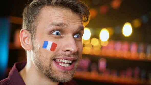 Joyful French Fan With Painted Flag Celebrating Team Victory, Making Yes Gesture