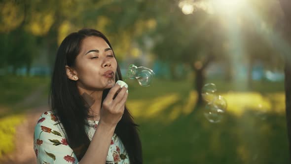 Asian Woman Blowing Soap Bubbles at the Sunset
